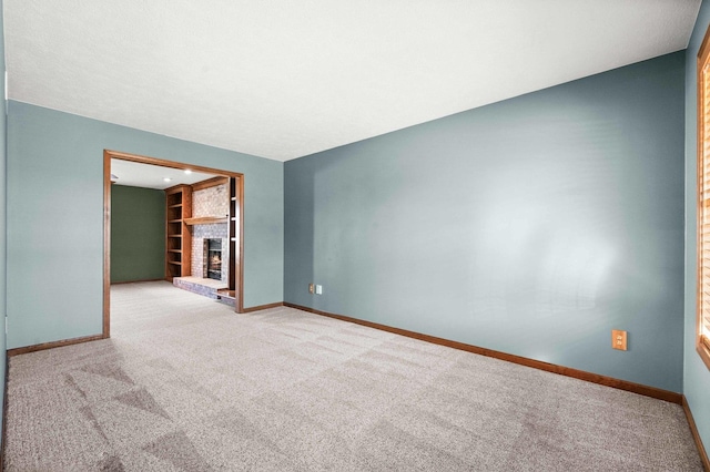 carpeted spare room featuring a fireplace, built in features, and baseboards