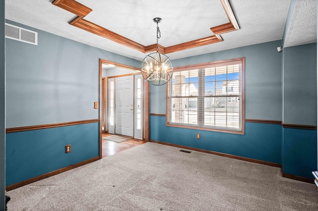 carpeted empty room with a textured ceiling, a raised ceiling, visible vents, and baseboards