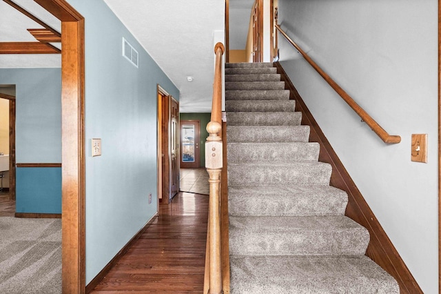 staircase with visible vents, baseboards, and wood finished floors