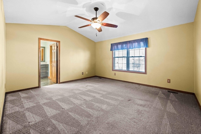 carpeted empty room with vaulted ceiling, visible vents, a ceiling fan, and baseboards