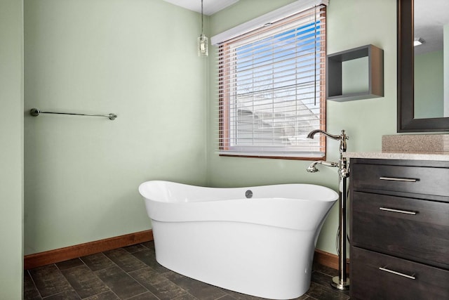 full bath with a soaking tub, vanity, and baseboards