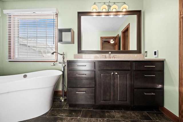 bathroom featuring a soaking tub, vanity, and baseboards