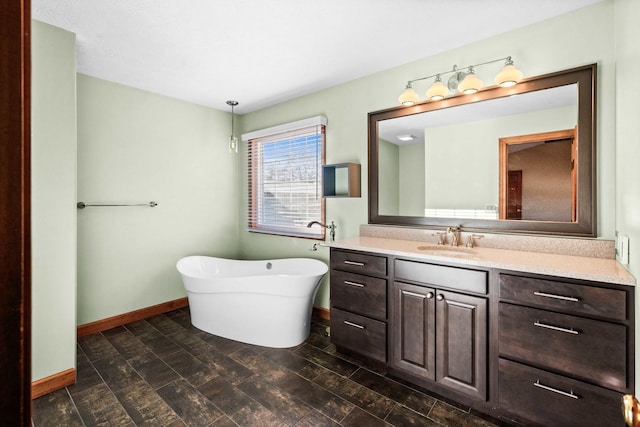 bathroom featuring a freestanding tub, baseboards, and vanity