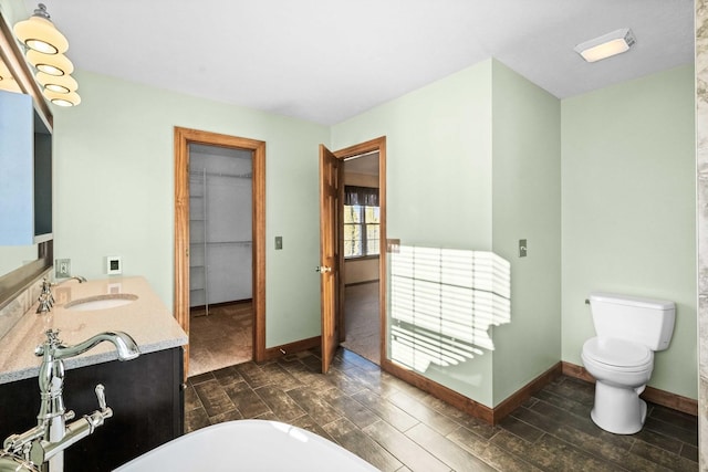 full bathroom with baseboards, a freestanding tub, toilet, and wood tiled floor