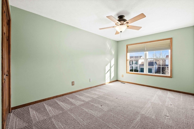 carpeted spare room featuring a ceiling fan, visible vents, and baseboards