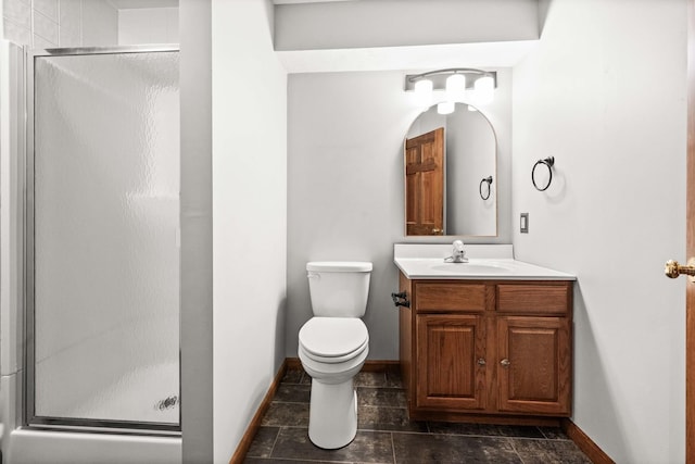 bathroom with toilet, a shower stall, baseboards, and vanity