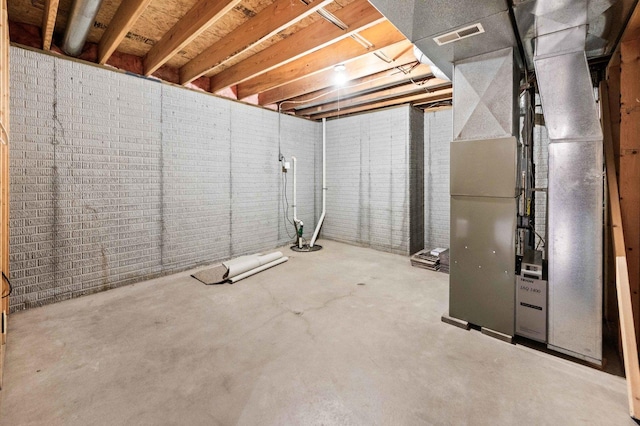 unfinished below grade area featuring brick wall, visible vents, and heating unit