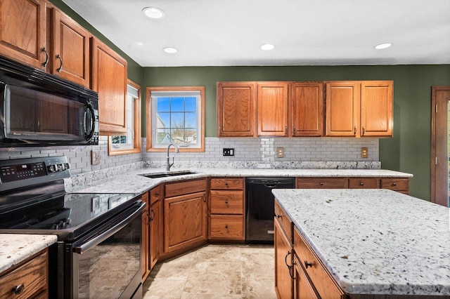 kitchen featuring light stone countertops, black appliances, brown cabinets, and a sink