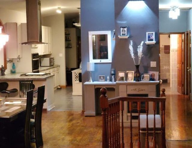 kitchen with white cabinets, black oven, light countertops, range hood, and stainless steel gas stovetop