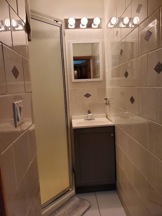 full bathroom featuring tile walls, tasteful backsplash, a shower stall, vanity, and tile patterned flooring