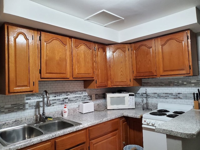 kitchen featuring white appliances, a sink, light countertops, decorative backsplash, and brown cabinetry