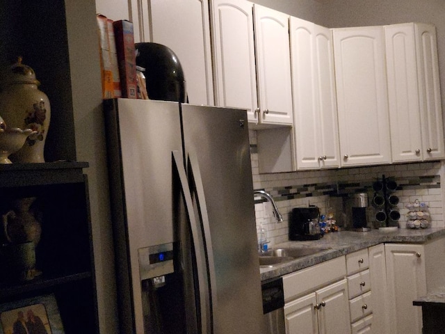 kitchen with backsplash, appliances with stainless steel finishes, white cabinets, and a sink