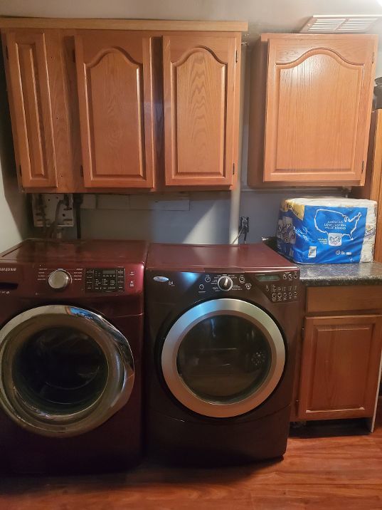 laundry area with visible vents, washing machine and dryer, cabinet space, and light wood-style floors