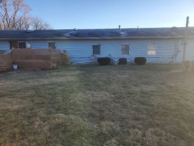 rear view of house featuring central air condition unit and a lawn