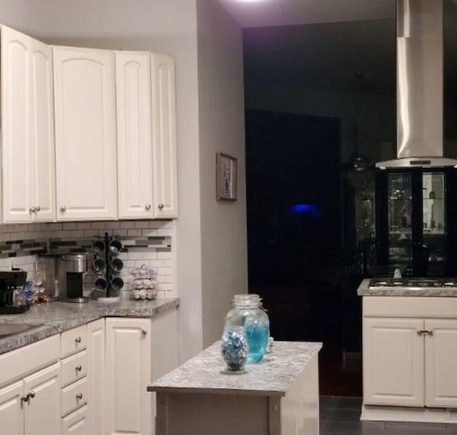 kitchen with tasteful backsplash, a kitchen island, extractor fan, white cabinetry, and stainless steel gas cooktop