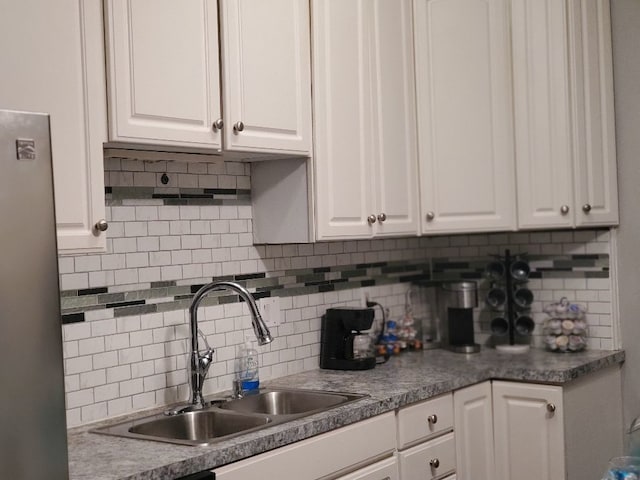 kitchen with freestanding refrigerator, dark countertops, a sink, and white cabinetry