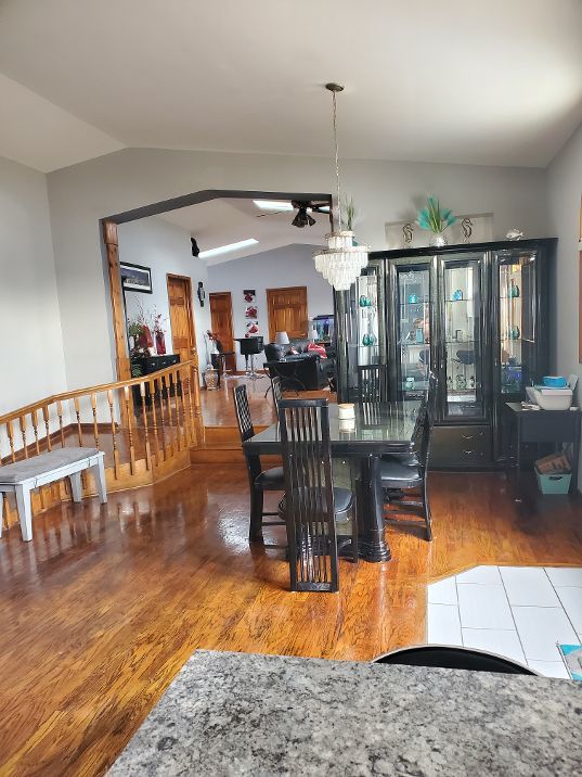 dining area with vaulted ceiling, wood finished floors, and a chandelier