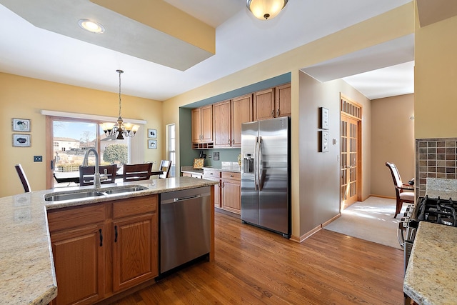 kitchen featuring dark wood-style floors, pendant lighting, stainless steel appliances, brown cabinetry, and a sink