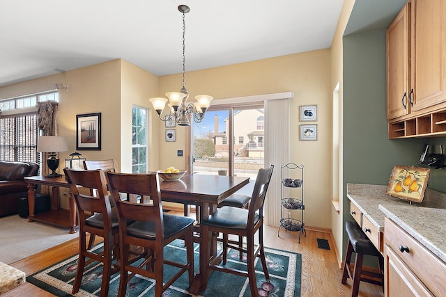 dining space featuring a notable chandelier, visible vents, a wealth of natural light, and light wood-style floors