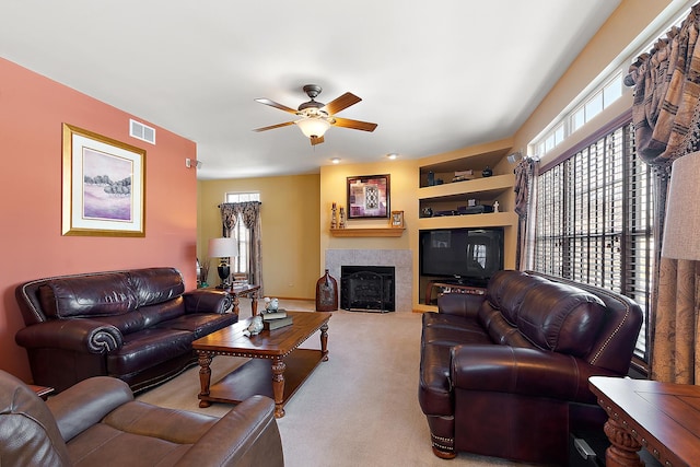 living area featuring light carpet, ceiling fan, a fireplace, and visible vents