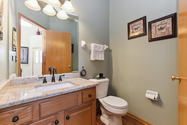 bathroom featuring toilet, baseboards, a notable chandelier, and vanity