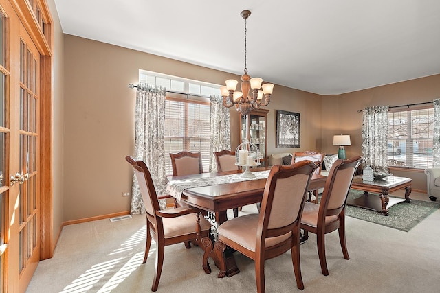 dining room with light carpet, visible vents, a chandelier, and a wealth of natural light