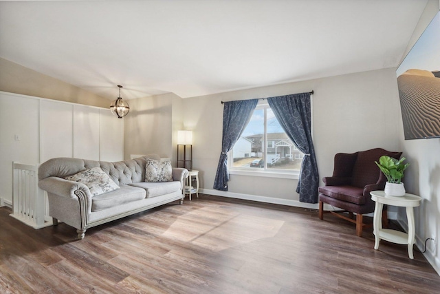 living room with an inviting chandelier, baseboards, and wood finished floors