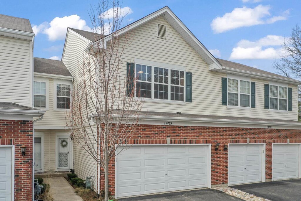 townhome / multi-family property with an attached garage, brick siding, and aphalt driveway
