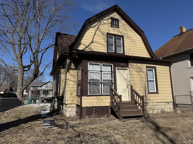 back of property featuring entry steps, fence, and a gambrel roof