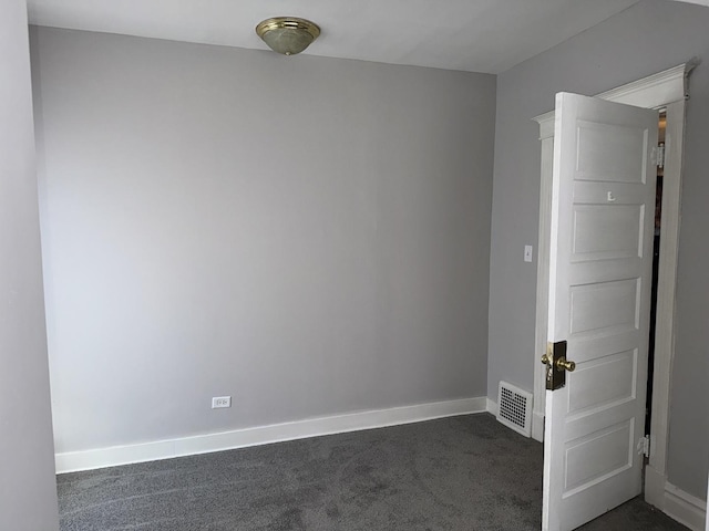 spare room with dark carpet, visible vents, and baseboards