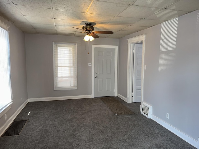 foyer featuring dark colored carpet, a drop ceiling, and visible vents