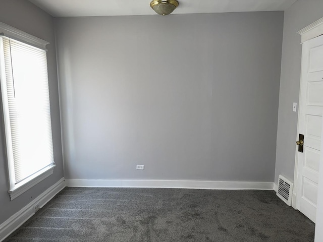 empty room featuring dark colored carpet, visible vents, and baseboards