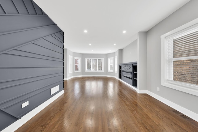 unfurnished living room with recessed lighting, wood finished floors, visible vents, and baseboards