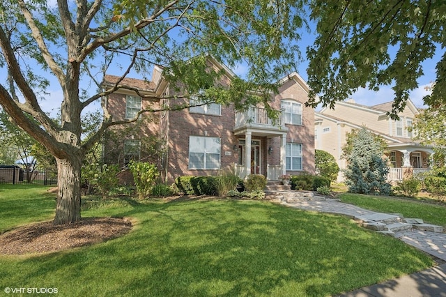 view of front facade featuring a front yard, brick siding, fence, and a balcony