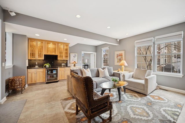 living room with wine cooler, baseboards, indoor wet bar, and recessed lighting