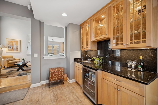 kitchen with beverage cooler, a sink, decorative backsplash, dark stone counters, and glass insert cabinets