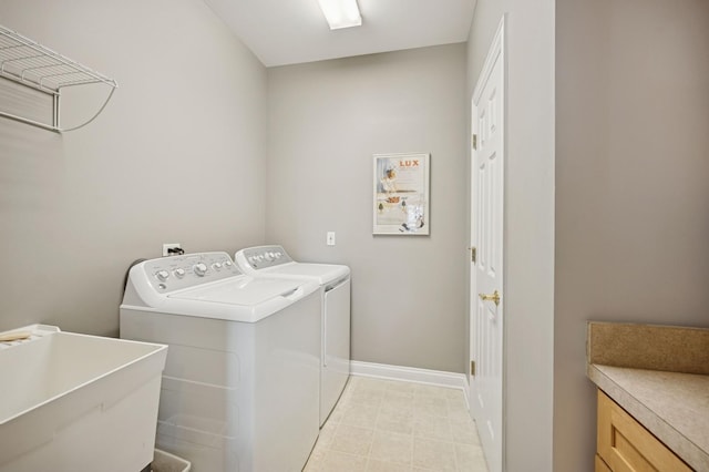 washroom with laundry area, a sink, washer and clothes dryer, and baseboards