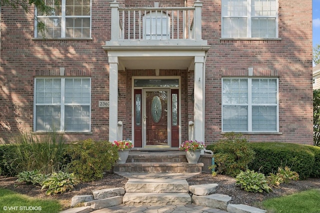 entrance to property featuring brick siding and a balcony