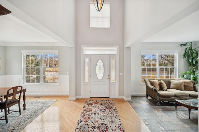 entryway featuring a healthy amount of sunlight, ornamental molding, and wainscoting