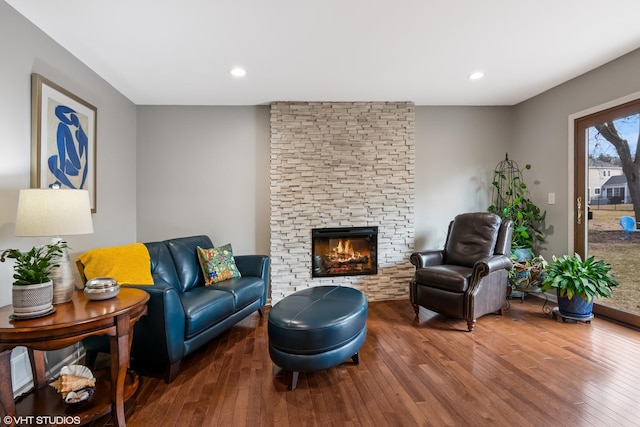 living room with hardwood / wood-style floors, a stone fireplace, and recessed lighting