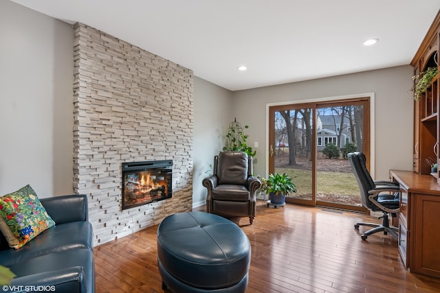 office featuring hardwood / wood-style floors, a stone fireplace, and recessed lighting