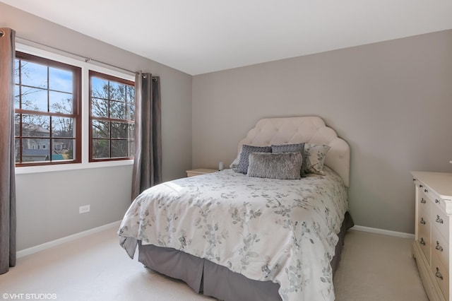 bedroom with baseboards and light colored carpet