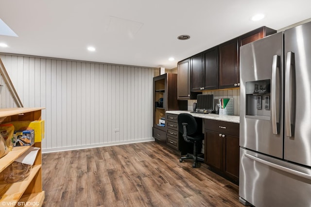 interior space featuring dark wood-type flooring, dark brown cabinets, stainless steel fridge with ice dispenser, and built in study area