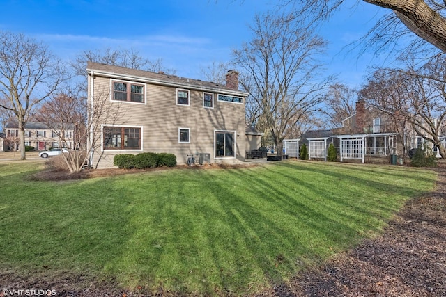 back of house with a lawn, central AC, and a chimney