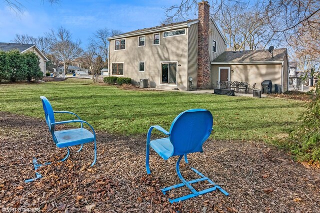 back of house with central AC unit, a lawn, and a chimney