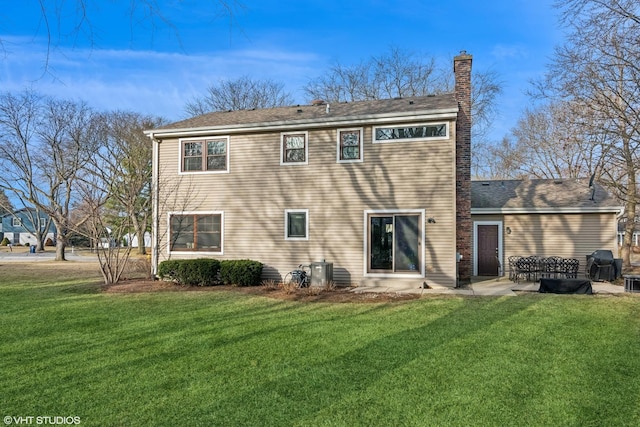 back of house with a yard, a patio, and a chimney