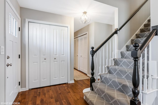 foyer with baseboards, stairs, an inviting chandelier, and wood finished floors