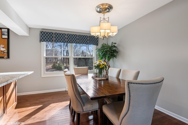 dining room featuring dark wood-type flooring, baseboards, and a chandelier