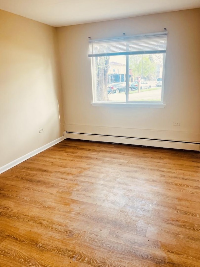 spare room with light wood-style floors, baseboards, and baseboard heating