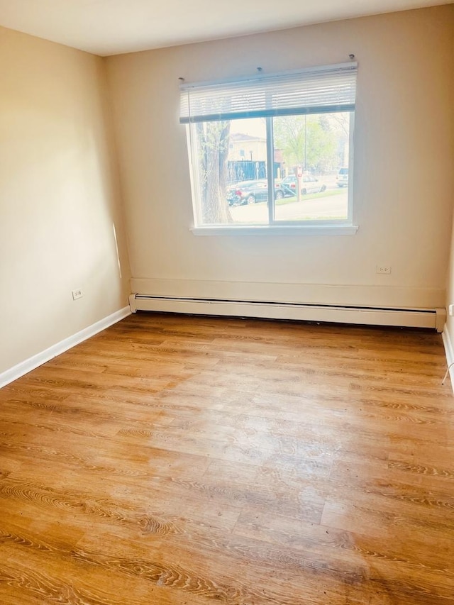 empty room with light wood-type flooring, baseboards, and baseboard heating